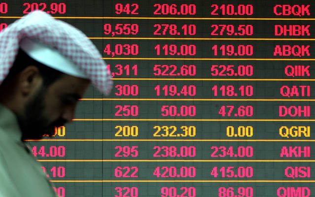 مستثمر يقف أمام شاشة التداولات داخل بورصة قطر