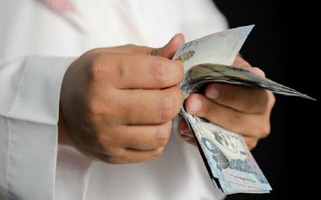 رجل يحصي نقوداً سعودية فئة 500 ريال