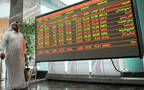 مستثمر يقف أمام شاشة التداولات داخل بورصة قطر