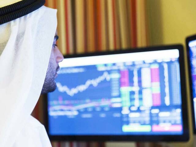 متعامل يتابع أسعار الأسهم المدرجة بسوق الأسهم الخليجية - أرشيفية