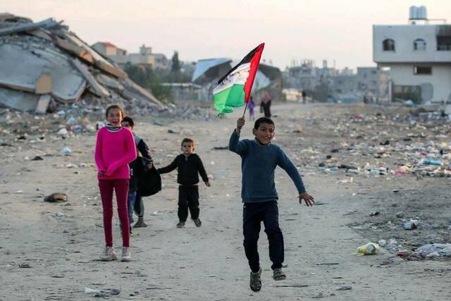 أطفال في غزة يلوحون بعلم بلادهم