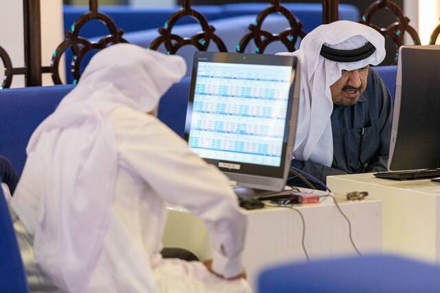 متعاملون يتابعون أسعار الأسهم بقاعة سوق دبي المالي